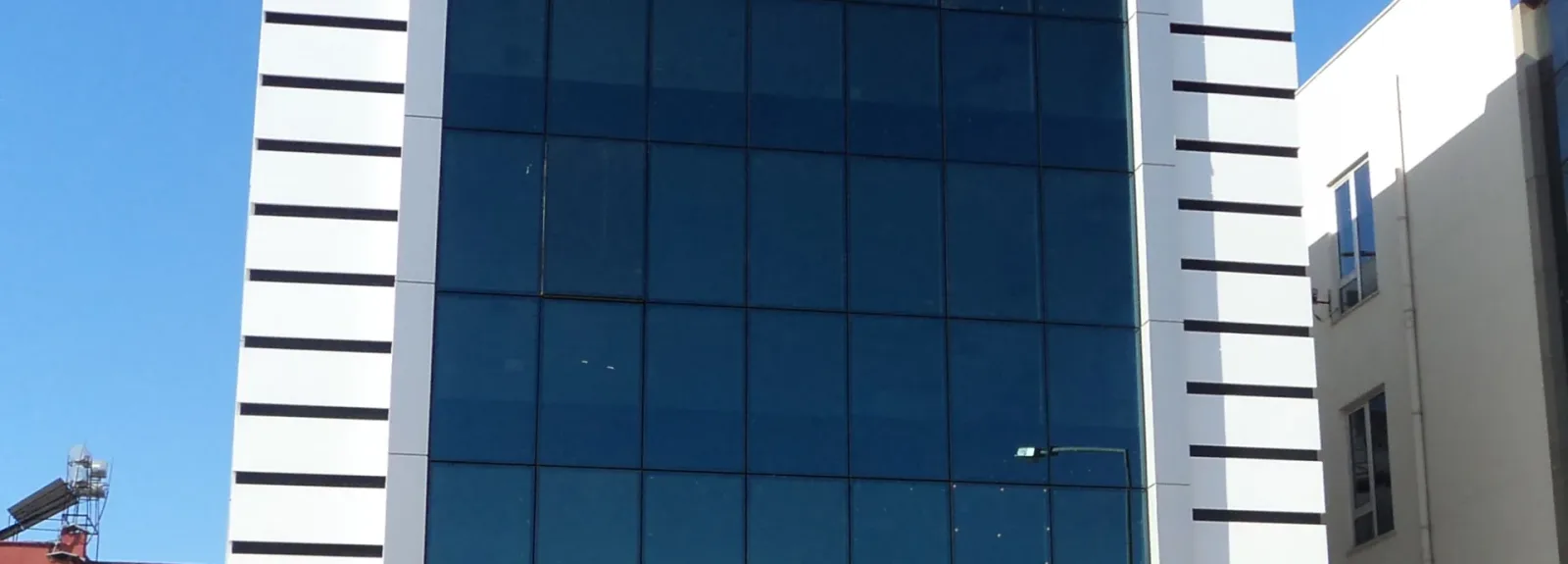 Mavi reflekte camlı giydirme cephe, yanlarında beyaz kompozit kaplama