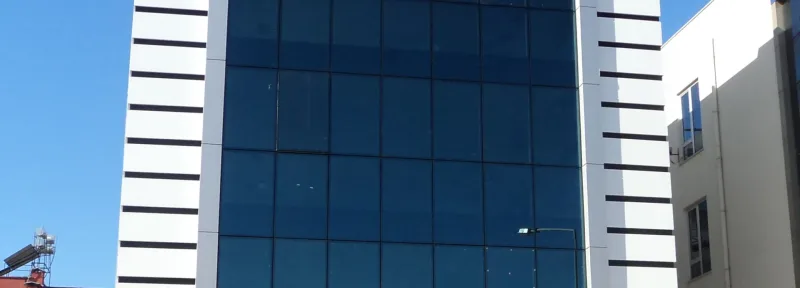Mavi reflekte camlı giydirme cephe, yanlarında beyaz kompozit kaplama